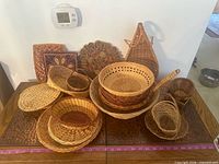 overview of all wicker baskets, woven jug, and embroidered trivets on table