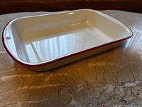 Top view of white enamel casserole dish showing interior, red rim, and hanging hole