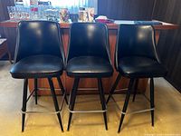 Front view of three matching black vinyl bar stools