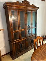 Full view of china cabinet showing upper glass doors, lower wood doors, carved crown