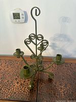 Front view olive green metal 5-arm candelabra showing scroll design and candle cups