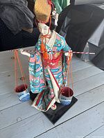 Full view of Maiko doll holding buckets on base