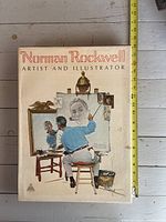Front cover of Norman Rockwell hardcover book with dust jacket and tape measure for scale