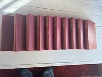 Ten red cloth volumes side-view showing uniform size