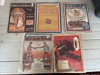 Five sheet music pieces laid out including The Battle at the Gates of Love, Khaki, After the War Is Over, Good-bye Broadway Hello France, The Hussars