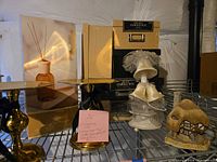 Full lot on wire shelf showing storage boxes, candle holders, bell topper, reed diffuser and cottage figurine