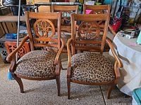 Front view of two matching wood dining chairs with animal print seats