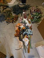 view of mixed artificial flower stems and foliage laid on basement floor
