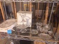 Shelf with all clear cut crystal pieces including pedestal centerpiece, oval tray, small bowls and dishes