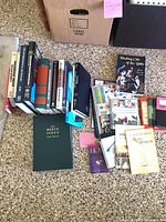 Entire group of books laid out on floor, showing hardcovers, paperbacks, Merck Index in foreground