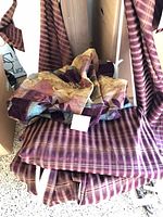 Pile of striped burgundy and brown curtains and valances