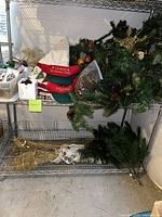 Overall lot on metal shelving showing wreath, hat, pine cones, greenery