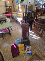 Full lot showing Eureka upright vacuum, spare cloth bag and three bag packs