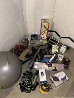 Wide view of lot showing stability ball, dumbbells, boxed thigh shaper, abs rower box, resistance bands, Pilates bar and other accessories