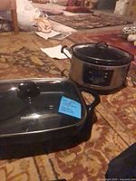 Slow cooker and electric skillet side by side on floor