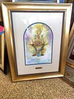 Full view of framed artwork showing gold frame, matting, print
