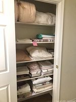 Full view of closet shelves filled with folded bedding and towels