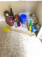 Group of glass vases, pitcher, decanter, wine bottle, tins, plastic pail, flyswatter, insect spray and mosquito coil boxes on floor