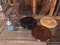 Lot overview showing jars, black plates, tan and copper chargers on wire rack
