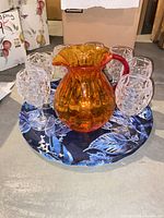 Amber pitcher and clear goblets on blue tray