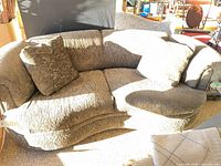 Front view of olive green curved sofa with two pillows