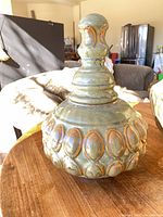 Large green ceramic jar with lid showing overall shape and glaze