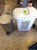 Stainless steel step trash can and white vented trash can side by side