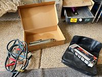 Lot overview showing jumper cables, timing light in box, lantern box, carrying case