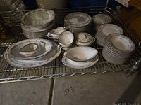 Full set stacked on metal rack showing plates, bowls, cups, saucers, serving pieces