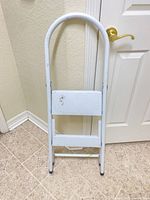 Stool folded showing front, arched handle and step surfaces