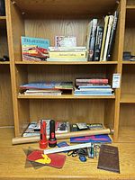 Overall view of shelves with books, flashlights and office items
