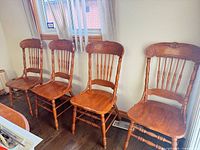 Four matching oak spindle back chairs side by side