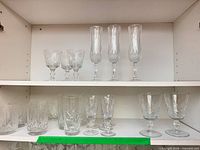 Two shelves filled with assorted cut crystal stemware and tumblers