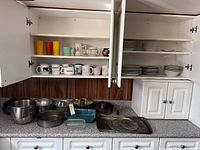 Open cabinets showing stacks of plates, bowls, mugs, tumblers