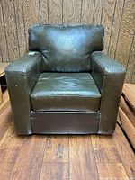 Front view of black leather armchair showing seat, arms and wear on cushion