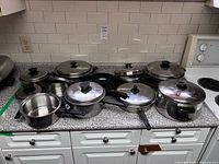 Group shot of all stainless steel pots, pans and lids on countertop