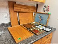 Overall lot showing wooden trays, ceramic and wood trivets, wicker tray, magnets