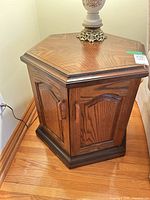 Front view of hexagonal wood veneer side table showing two doors and base