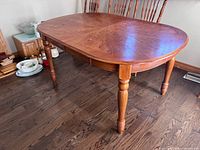 Full view of wooden dining table with turned legs on hardwood floor