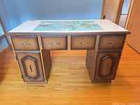 Front view of the desk showing laminate map top, drawers, cupboard doors