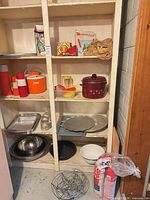 Full view of shelving unit showing thermoses, bowls, bakeware, enamel pot, trays and floor items