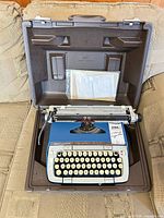 Typewriter seated in open carry case with papers in lid