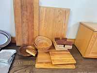 Group shot showing six wood cutting boards, carved bowl, wicker baskets and napkin holders