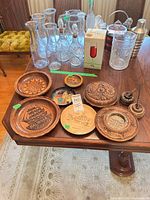 Group shot of all carved wooden plates/dishes, metal plate, ashtray and pens
