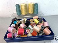 Tray of assorted small thread spools with four large cones behind