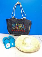 Overview of tote bag front, straw hat, blue flip flops