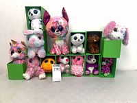 Full group of 13 big-eye plush animals displayed in green boxes