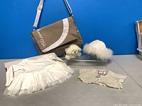 All five items arranged: Billabong bag, baby dress, crochet sweater, hat, plush dog