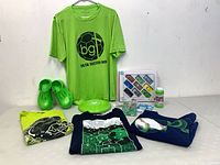 Group shot showing all items including Crocs, four t-shirts, Hot Wheels pack, frisbee, bubble bottle, novelty packs