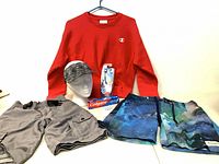 Full lot view showing all items: Gap cargo shorts, Champion sweatshirt, visor on head form, Colgate toothpaste, Tooth Tunes toothbrush, galaxy boardshorts